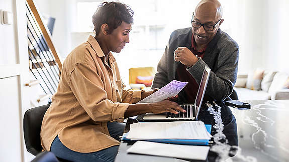 retired happy couple looking over finances on a laptop