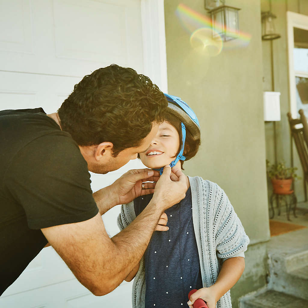 Dad putting on bike helmet on child