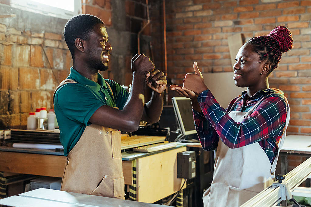 An employee in a warehouse using American Sign Language with a co-worker(s)