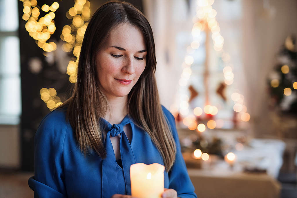 A contemplative (but not depressing) image of someone admiring a memory candle or people hugging during the holidays