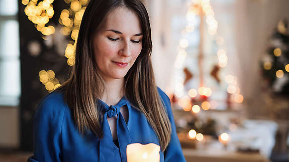 A contemplative (but not depressing) image of someone admiring a memory candle or people hugging during the holidays