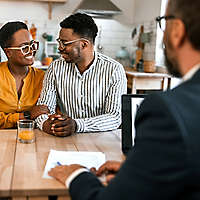 couple smiling at each while in meeting with financial advisor