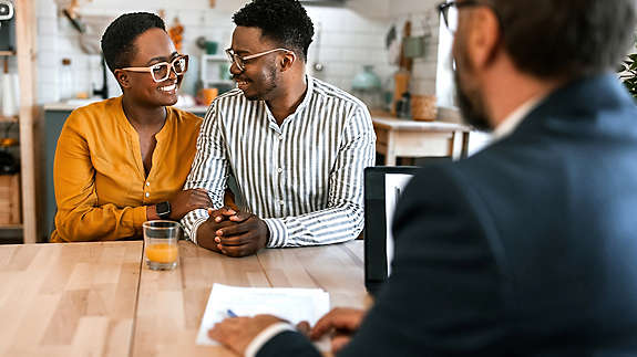 couple smiling at each while in meeting with financial advisor