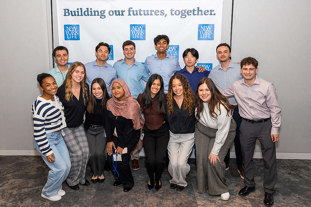 group of interns smiling behind New York Life wallpaper