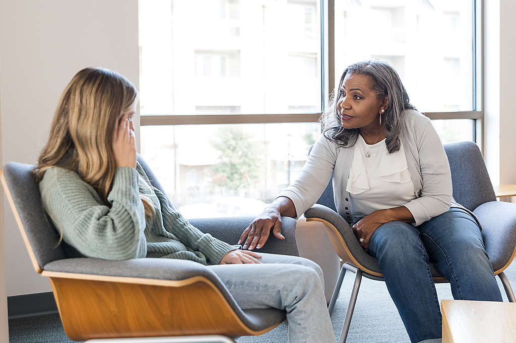 mature woman talks with young adult female to give her some support and advice
