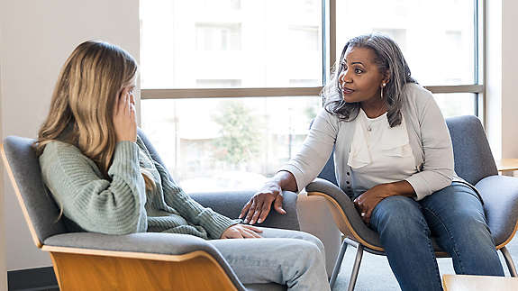 mature woman talks with young adult female to give her some support and advice