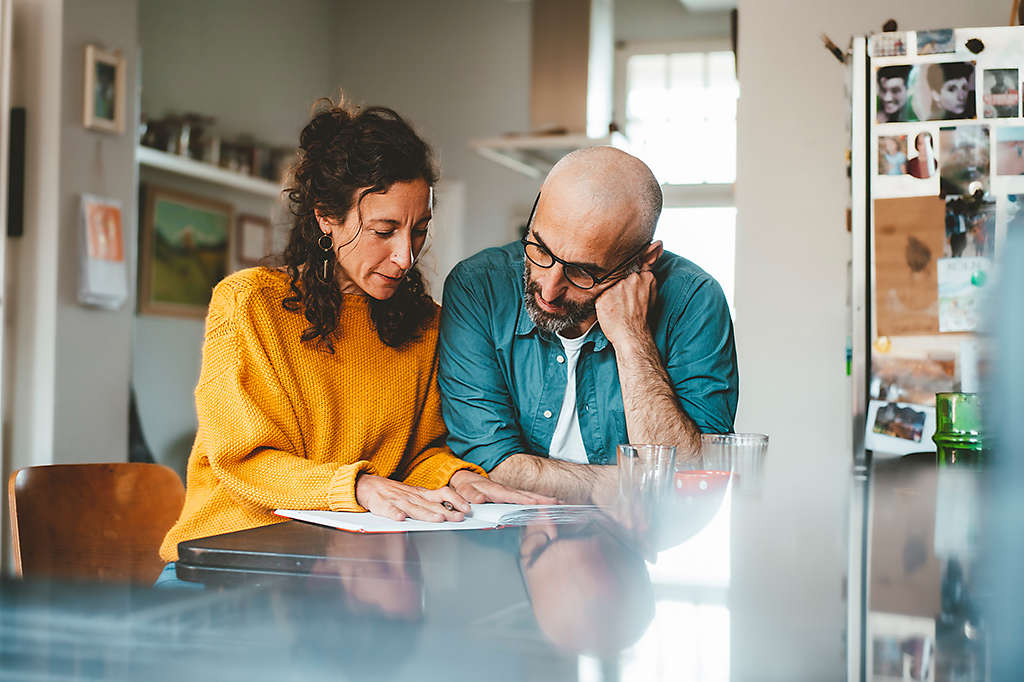 middle aged married couple preparing financial bills at home
