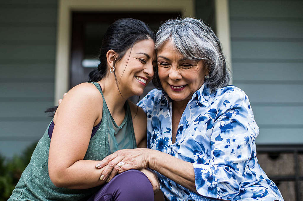 Senior woman and adult daughter laughing on porch