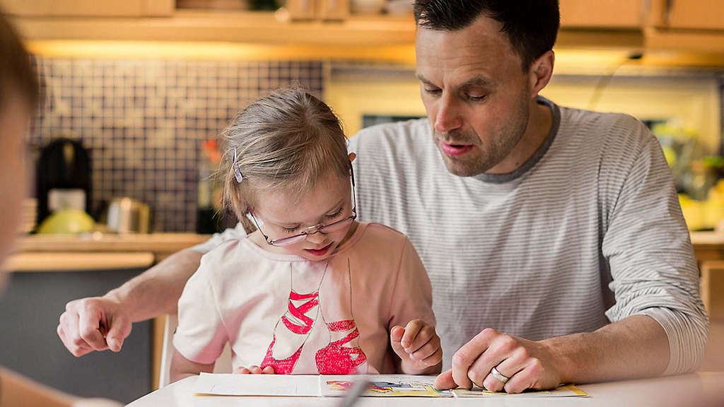 Father playing with daughter at table.