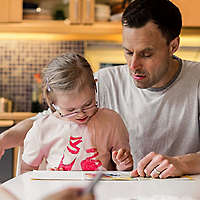 Father playing with daughter at table.