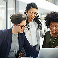 A group of women in an office looking at a laptop and researching 401(k)s
