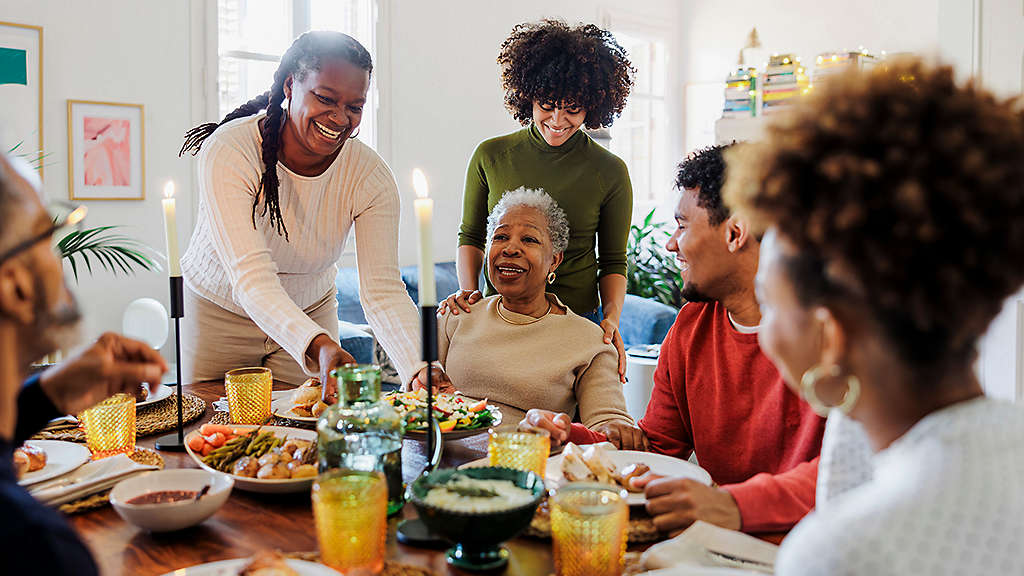 Happy family is sitting at the table and having dinner together