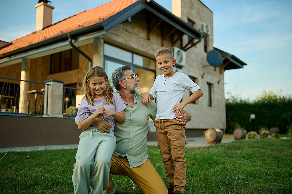 Grandfather with grandchildren and the house he intends to pass down to them