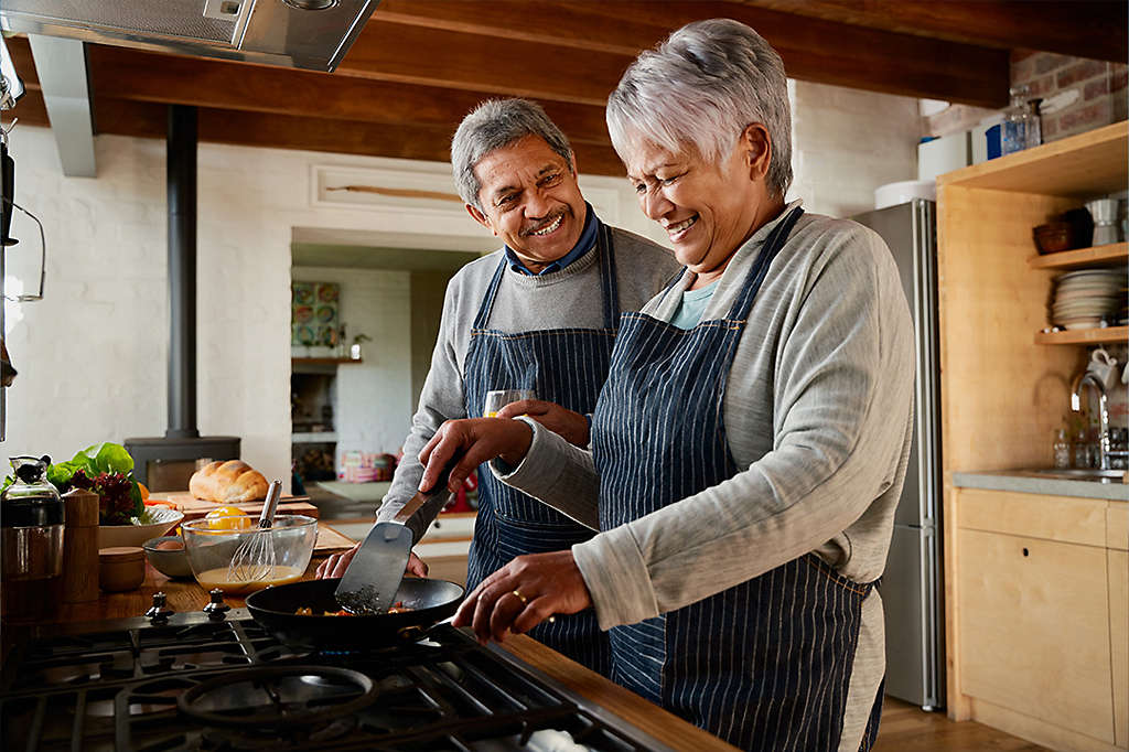 Elderly multi-ethnic couple laughing together in the kitchen