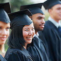 Young college graduates holding their diplomas while standing in a row and smiling