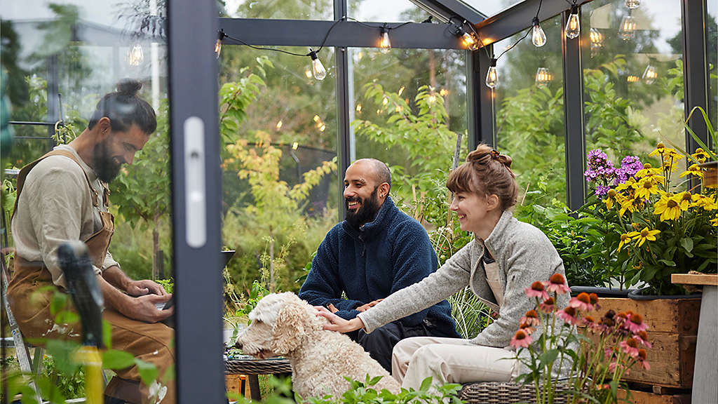 Smiling friends sitting in greenhouse