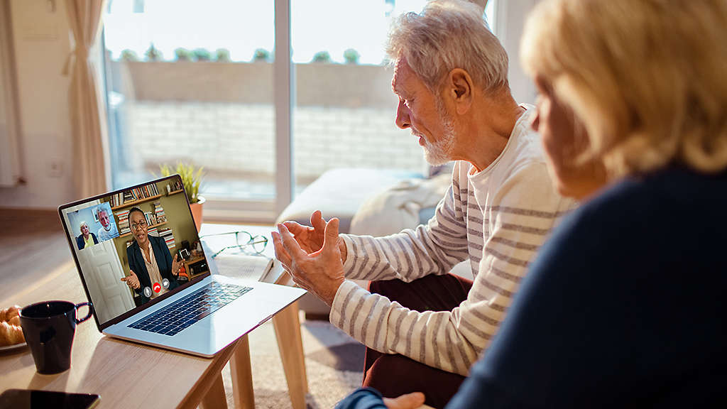 Senior couple on a video call with financial advisor using a laptop at home
