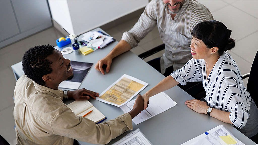 Happy businesswoman handshaking with manager in meeting