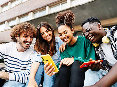 Group of university student friends sitting together using mobile phones to share content on social media