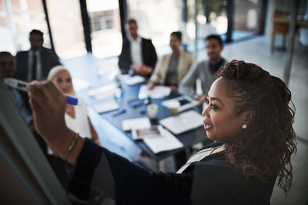 Businesswoman confidently giving a presentation to work colleagues in a boardroom