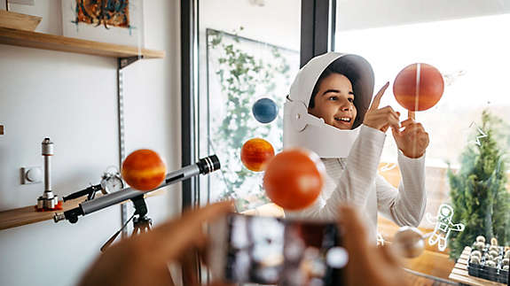 Parent using phone to record child playing in spacesuits 