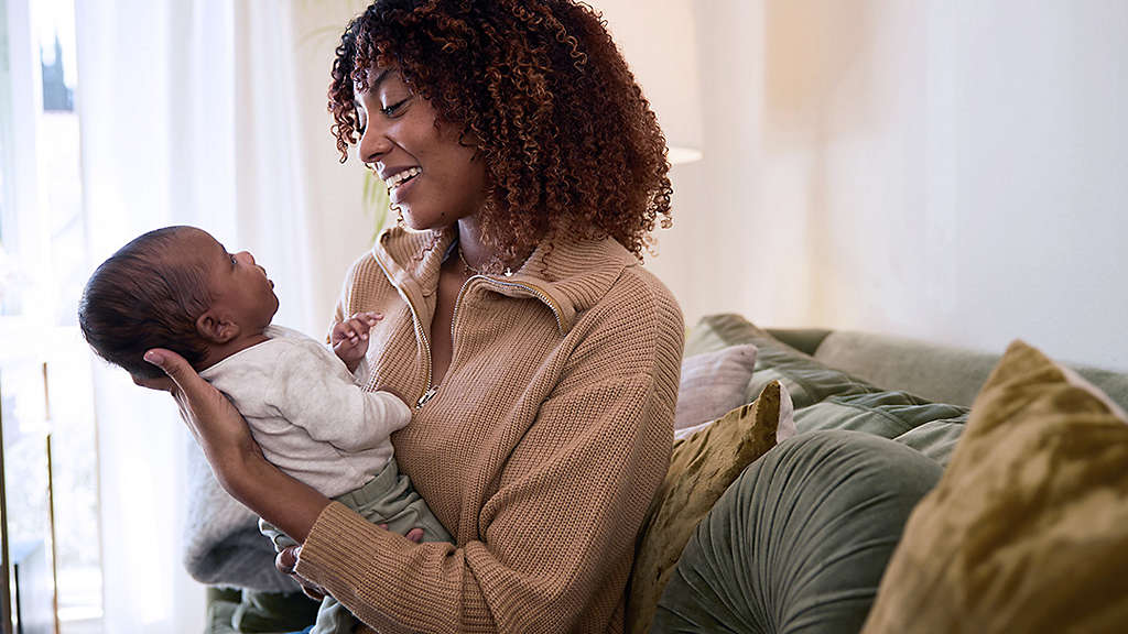 Mom holding her little baby son in her arms at home