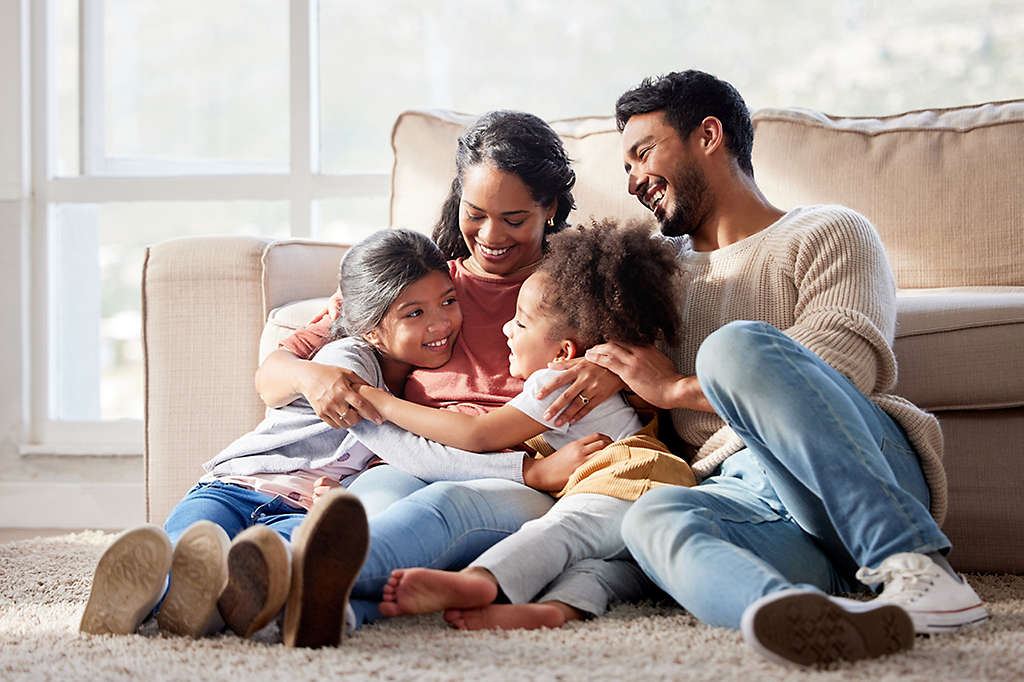 Happy family with two daughters hugging their mother and bonding at home.