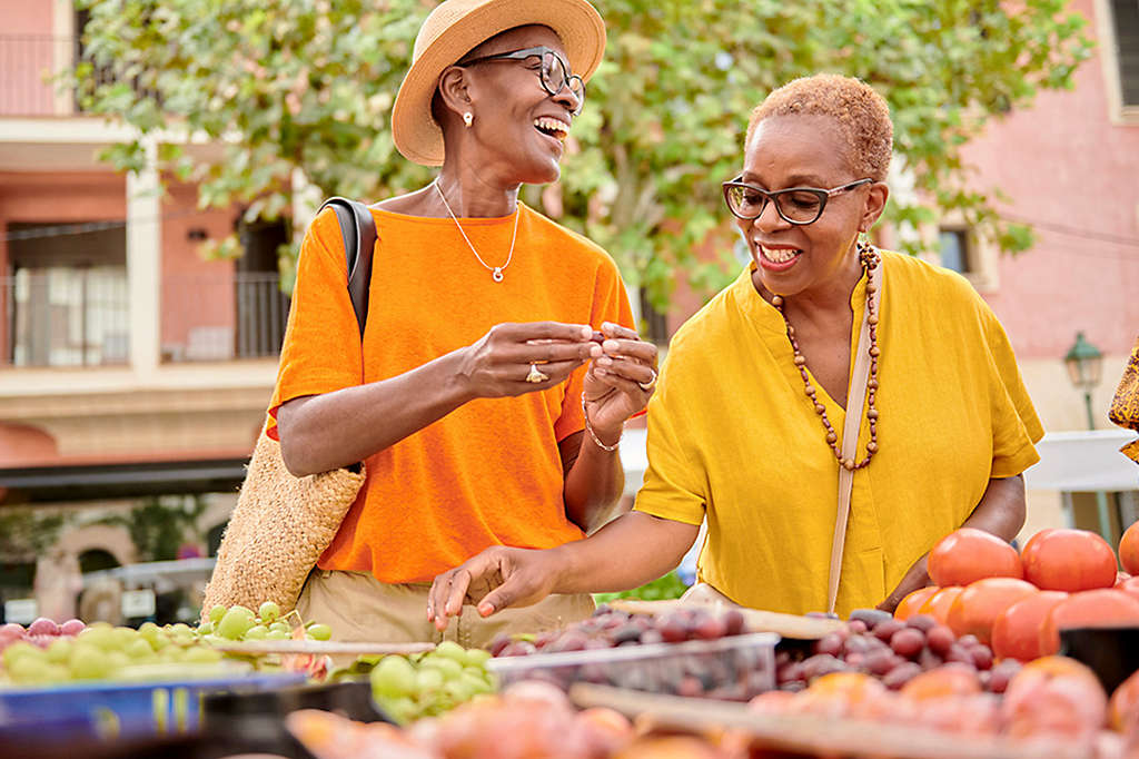 Two women at a farmers market buyingfruits