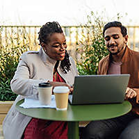 Coworkers discussing project and having work meeting at rooftop garden in high-rise office building