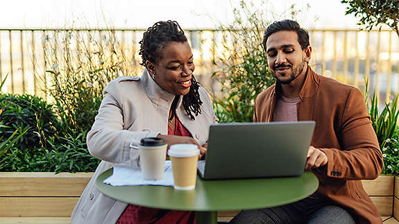 Coworkers discussing project and having work meeting at rooftop garden in high-rise office building