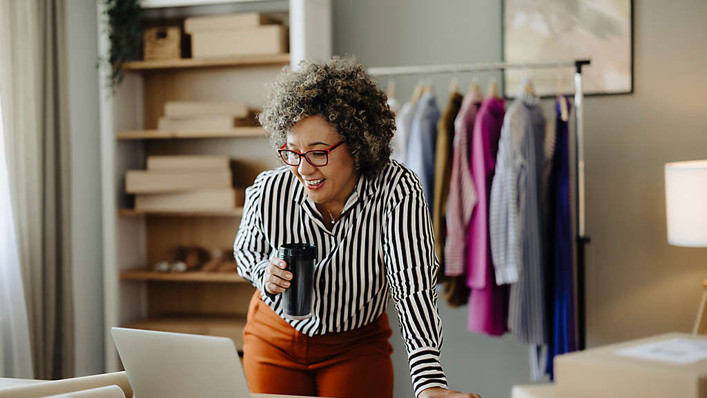 Female small owner drinking coffee while working in her online cloth shop