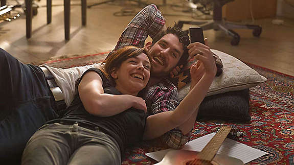 A couple cuddling and smiling on a sofa