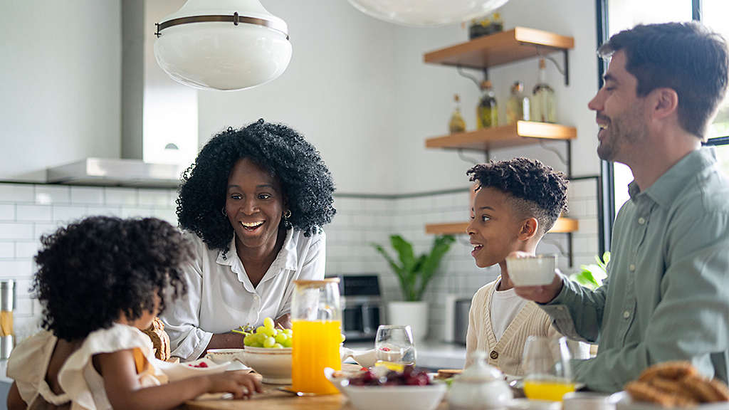 A happy family sharing a breakfast together around a kitchen island.