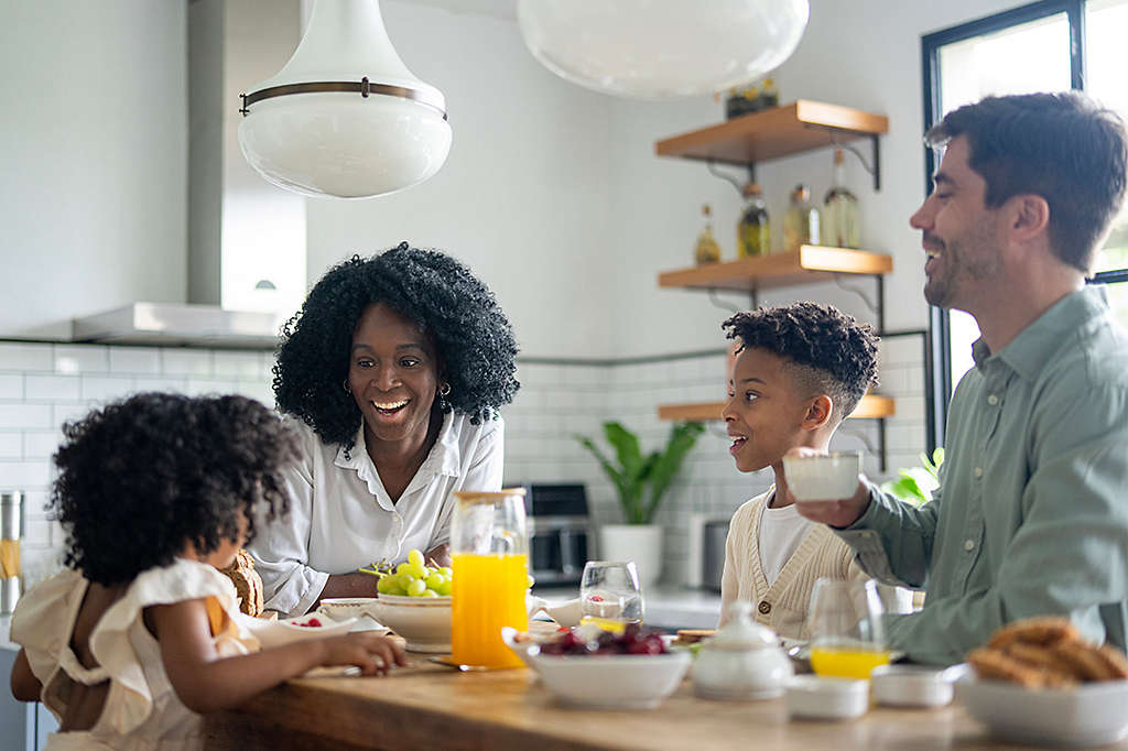 A happy family sharing a breakfast together around a kitchen island.