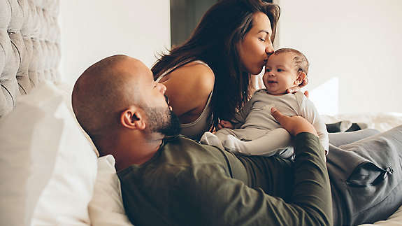 New family laying down on bed