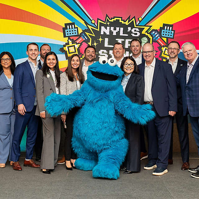 NYL Employees stand with the Sesame Street character Cookie Monster