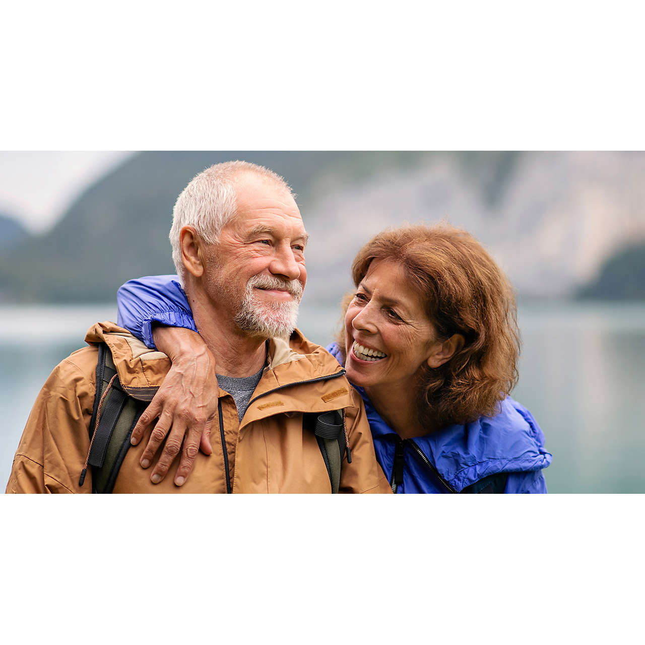 Senior couple hiking by lake in nature resting