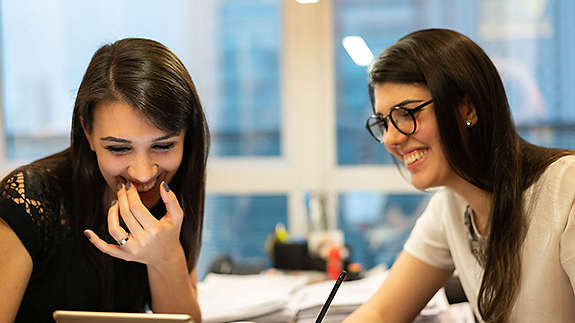 Two young women laughing over coffee
