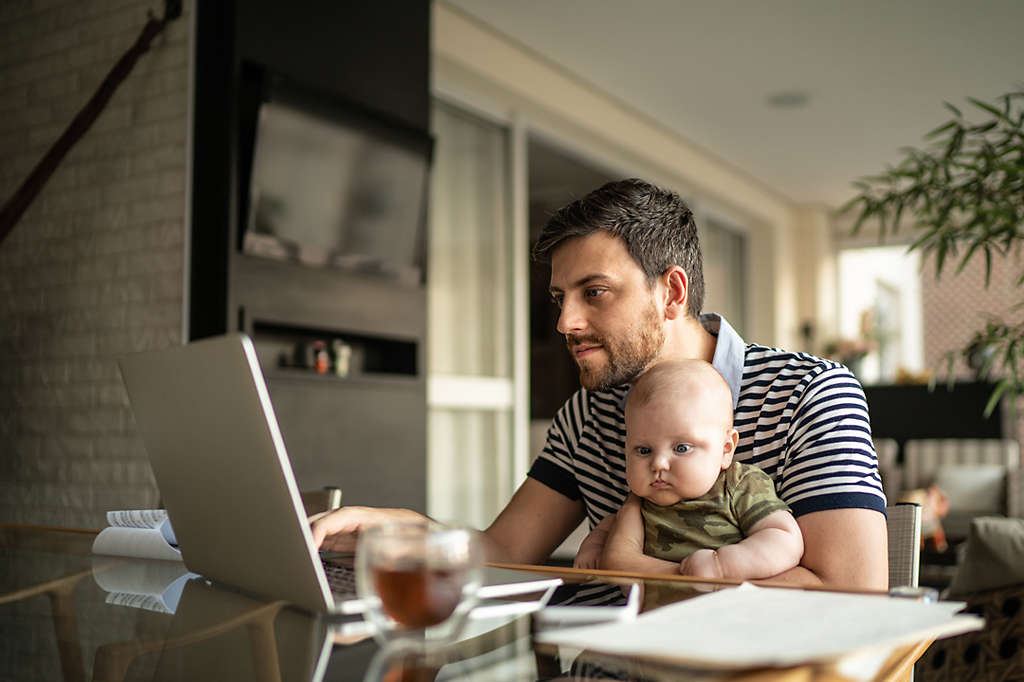 Father and baby sitting at a computer while the father invests