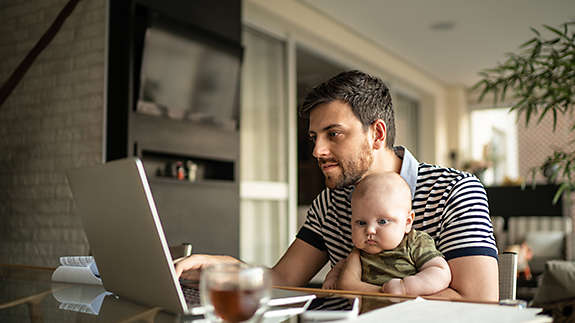 Father and baby sitting at a computer while the father invests