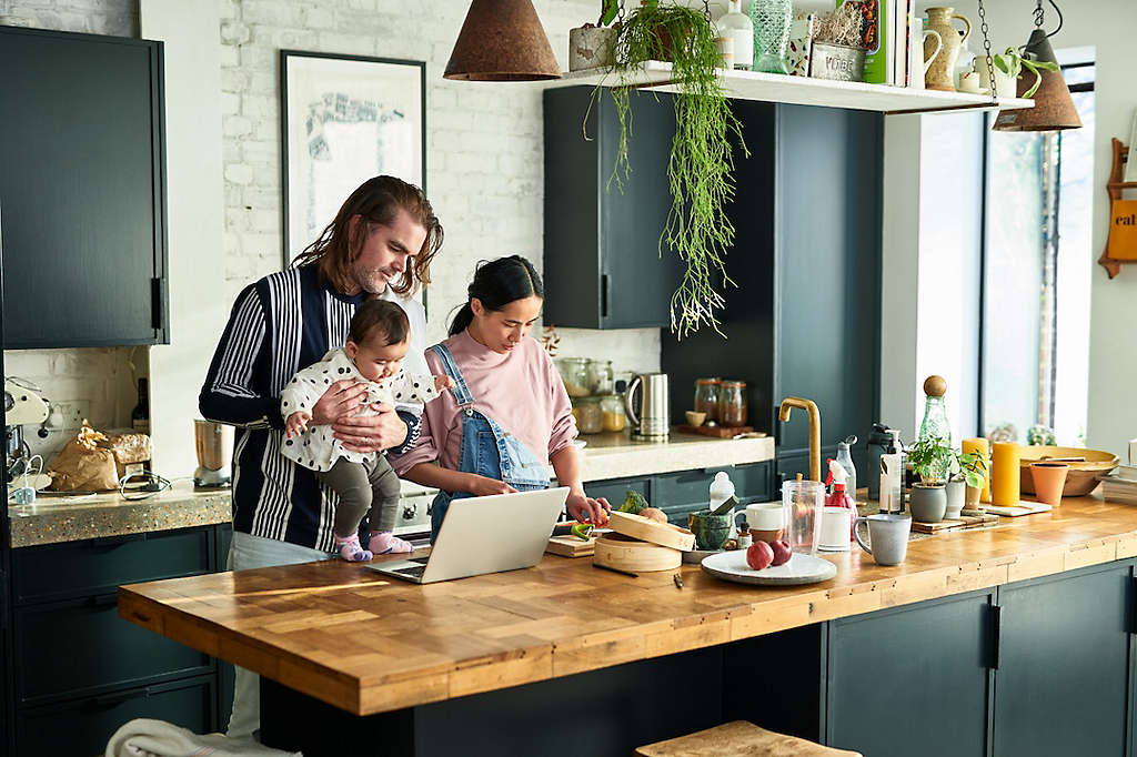Young couple cooking dinner and spending time with their baby