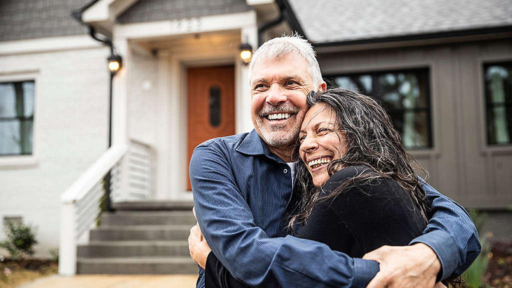 Portrait of senior couple in front of home