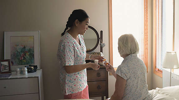 A home care provider helping an elderly woman with her prescriptions.