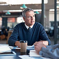 A business owner discusses succession planning with his partner at a boardroom table.�