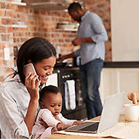 A woman sits with her young child at a computer as she starts a 529 college savings plan with help over the phone from an agent.