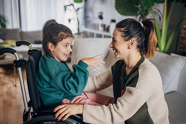 happy caregiver spending time with special needs child in wheelchair