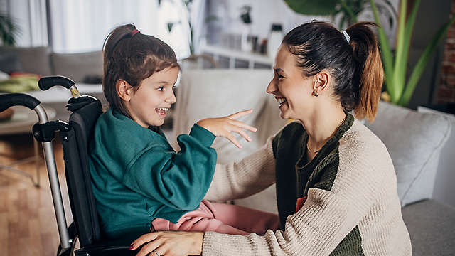 happy caregiver spending time with special needs child in wheelchair