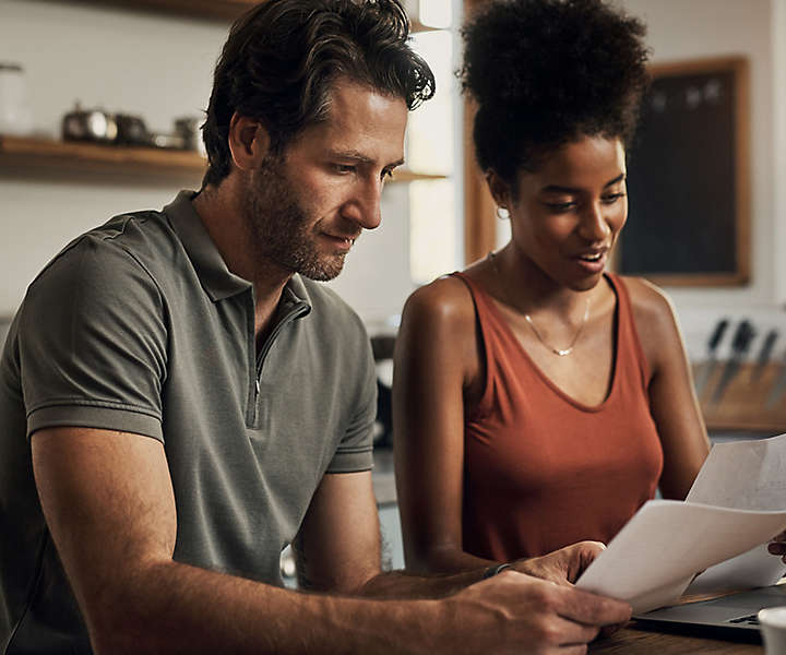 Young couple reviewing financial documents at their kitchen table