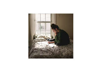 woman on her bed writing in a journal