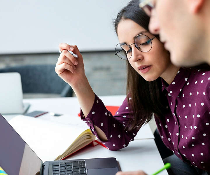 Woman and man working on laptop in an office